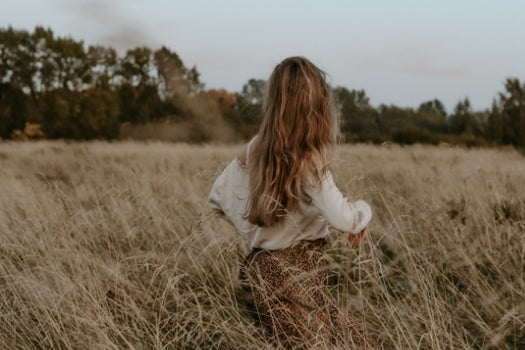 woman running away from camera through wheat field