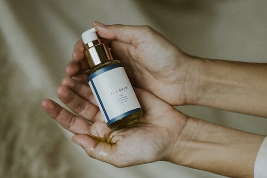 Two hands holding oil based facial cleanser tui