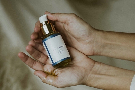 Two hands holding bottle of tui oil based facial cleanser