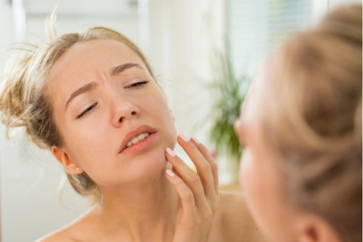 woman examining dry skin in the mirror