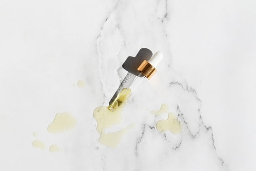 skincare oil dropper lying on marble background with oil on surface