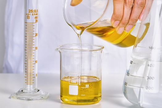 pouring skincare oil botanical blend from breaker to beaker in a science setting