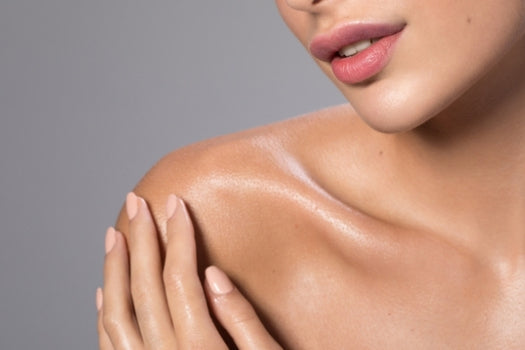 woman caressing healthy glowing skin on shoulder and chest