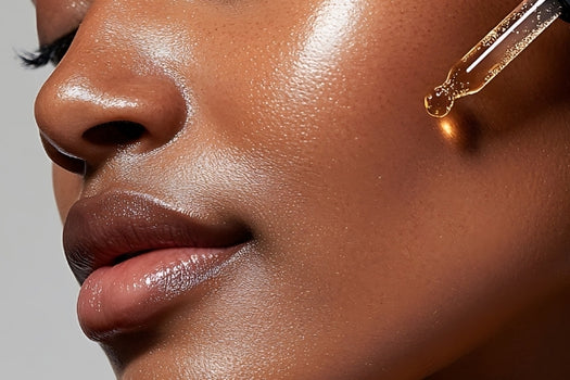 Dark skinned woman dispensing skincare oil onto cheek