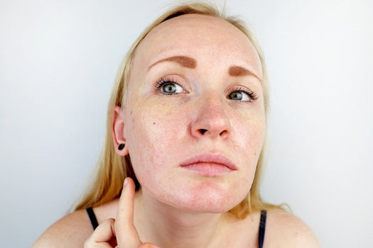 Woman examining oily skin in mirror