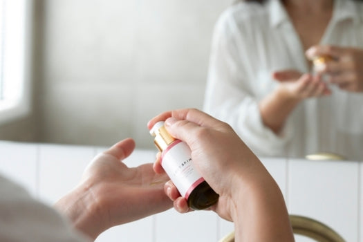 pumping dry skin facial serum into hand in front of mirror
