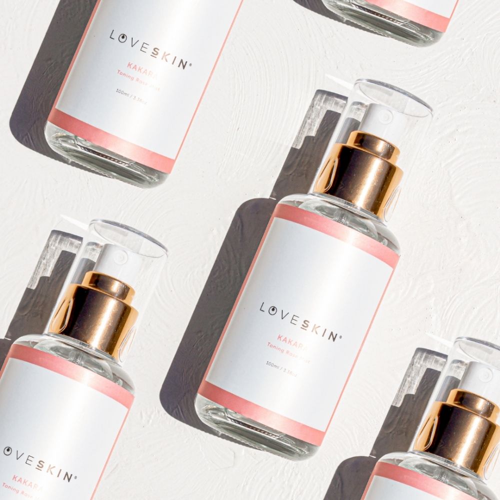 LOVESKIN KAKARA Toning Mist bottle with rose gold accents lying on a white textured surface, natural skincare flat lay.