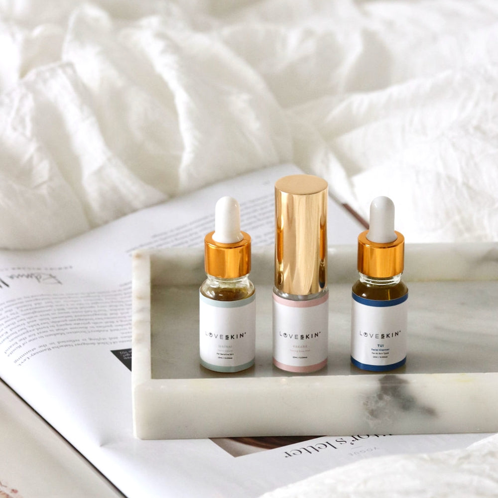 Three step skincare serum bottles on a marble tray with a white fabric background