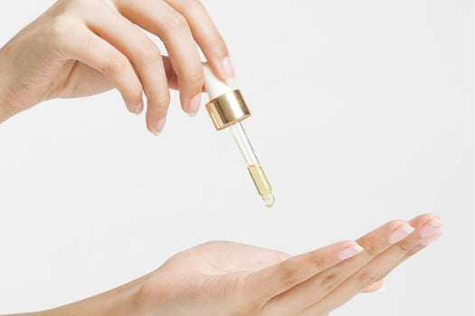 hand squeezing loveskin serum oil dropper into open palm