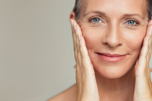 Older woman with healthy skin close up looking into camera holding face in palms