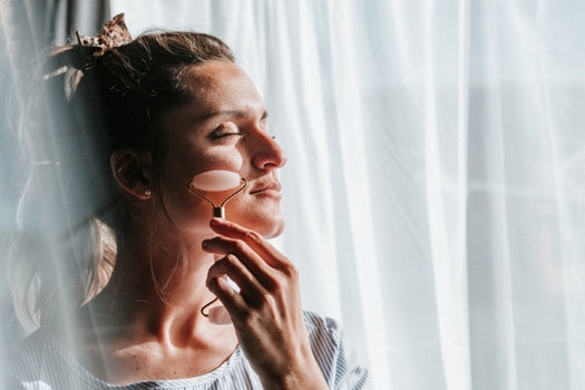 woman using facial roller with serum
