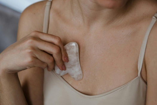 woman using natural gua sha tool across chest