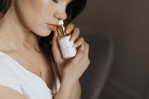 Woman holding bottle of rose toning mist near face