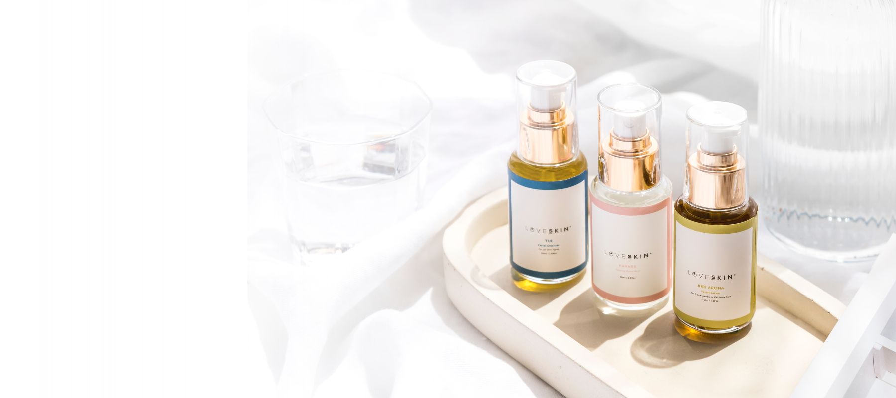 Three skincare serum bottles on a white tray with a white background