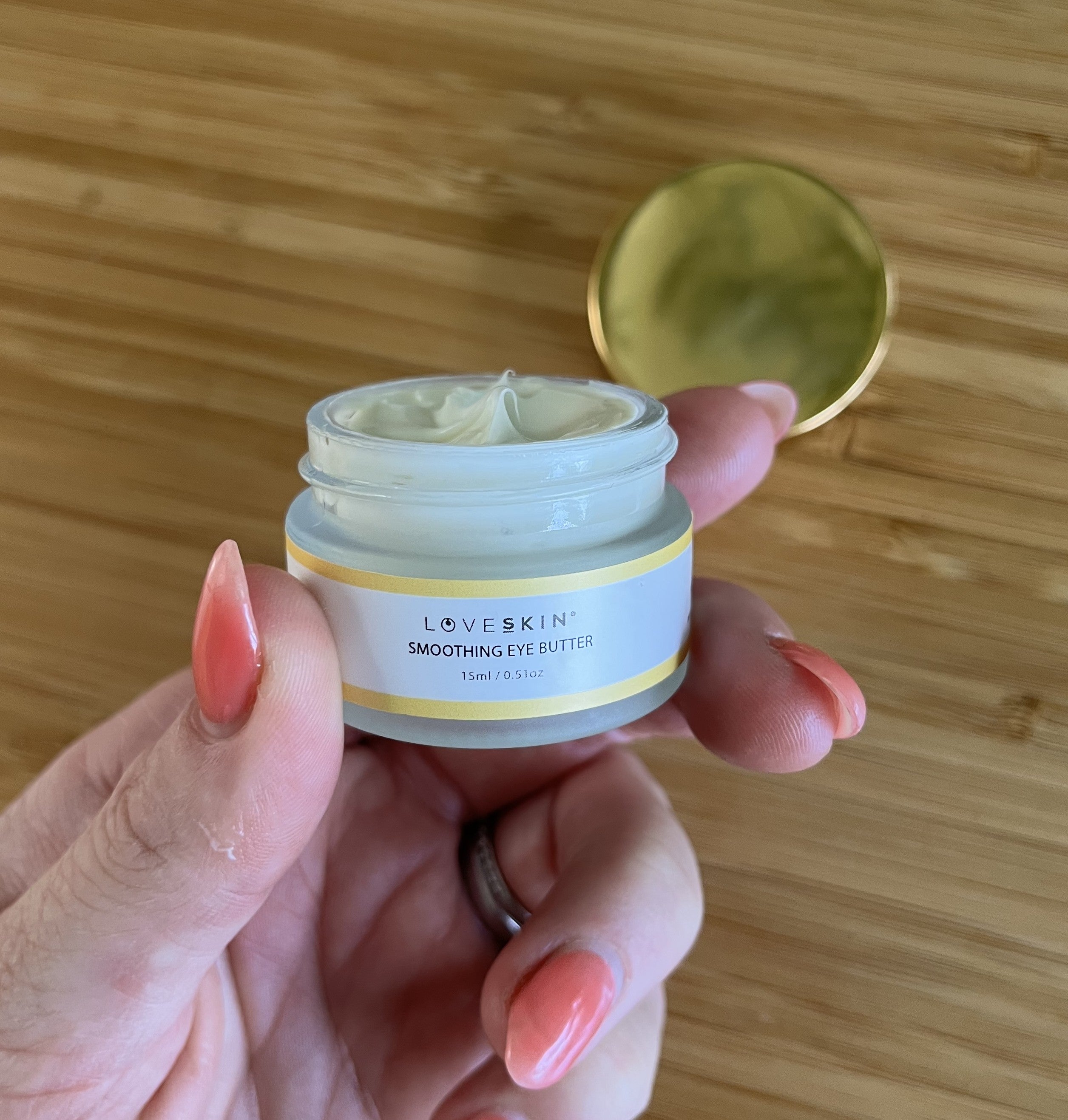 Hand holding a jar of thick under eye cream, Smoothing Eye Butter