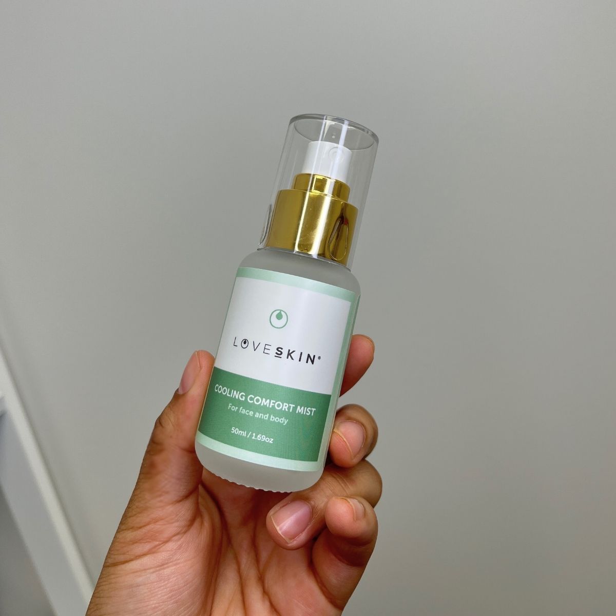 Hand holding a bottle of LOVESKIN Cooling Comfort Mist for menopause support including hot flashes