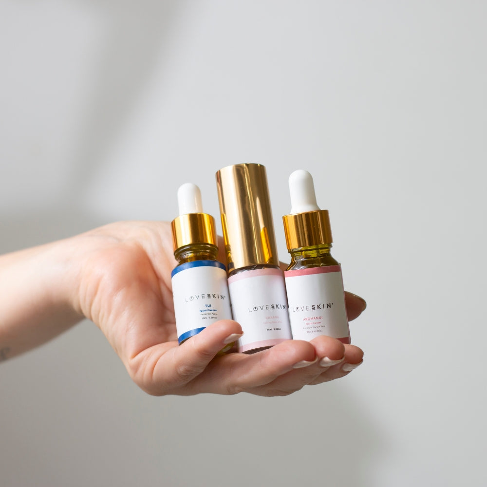 Hand holding LoveSkin travel skincare ritual towards the camera, with a neutral background.