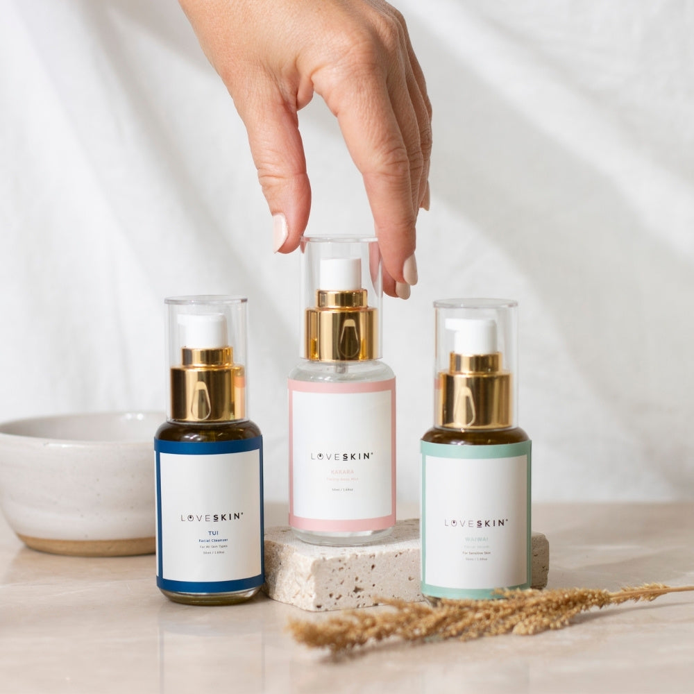 Three natural NZ made skincare bottles for sensitive skin, rose facial toning mist being picked up by a hand.